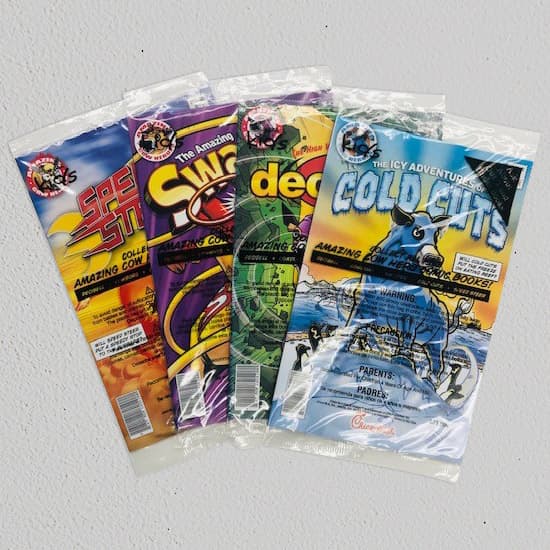 4 comic books in overwrap packaging spread out in a line stacked partially on each other